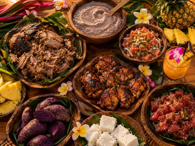 Hawaiianisches Luau-Festmahl mit Kalua-Schwein, Poi, Poke, Ananas und einem Mai Tai